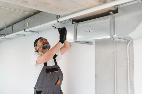hvac technician installing metal air duct