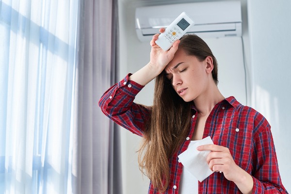 sweating woman holding ac remote control